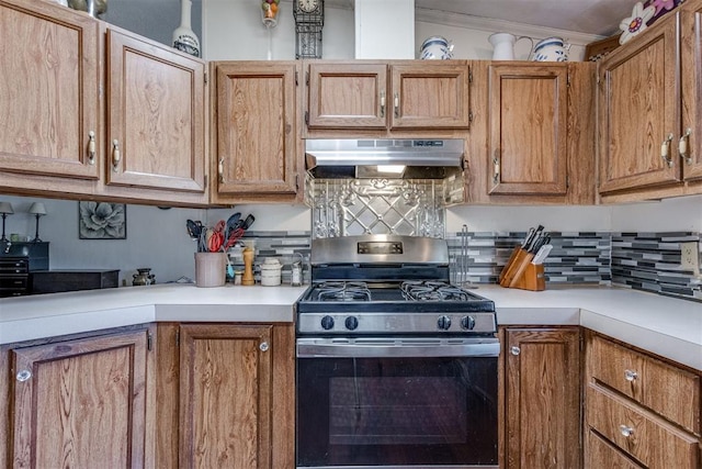 kitchen with under cabinet range hood, backsplash, light countertops, and stainless steel range with gas cooktop