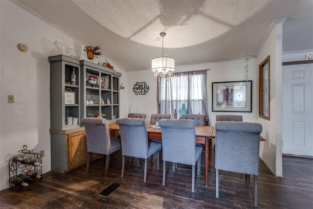 dining area featuring wood finished floors, an inviting chandelier, lofted ceiling, a textured ceiling, and crown molding