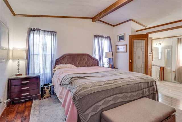 bedroom with ensuite bath, lofted ceiling with beams, wood finished floors, and ornamental molding