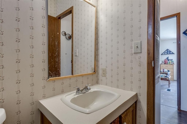 half bath with wallpapered walls and vanity