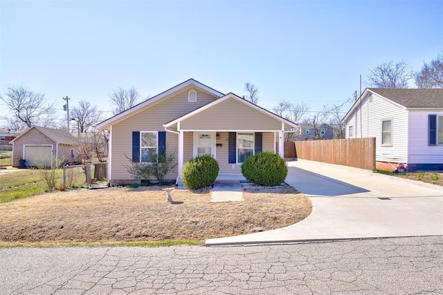 bungalow featuring concrete driveway, fence, and covered porch