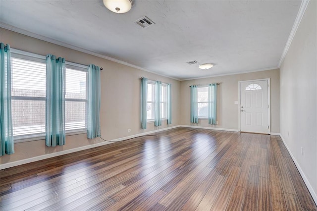 interior space featuring visible vents, crown molding, baseboards, and wood finished floors