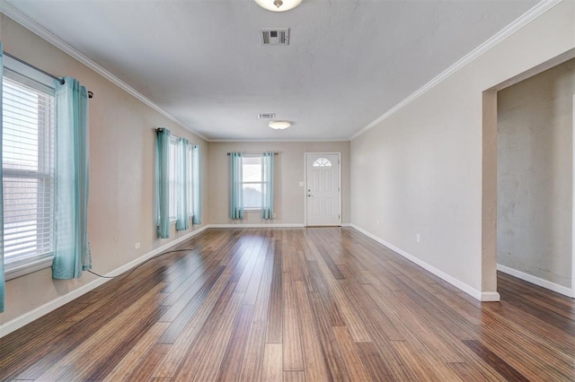 unfurnished room with visible vents, ornamental molding, baseboards, and wood finished floors