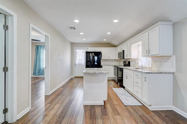 kitchen featuring wood finished floors, visible vents, a kitchen island, decorative backsplash, and black appliances