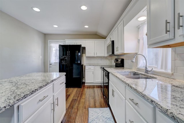 kitchen featuring light stone countertops, dark wood finished floors, a sink, black appliances, and white cabinets