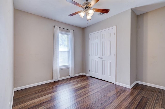 unfurnished bedroom featuring a ceiling fan, visible vents, baseboards, dark wood-style flooring, and a closet