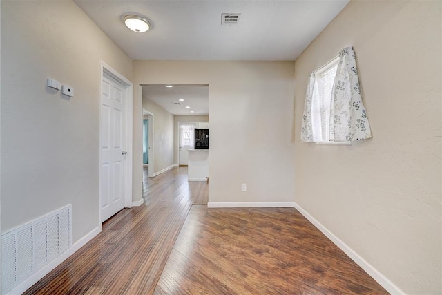 empty room featuring wood finished floors, visible vents, and baseboards