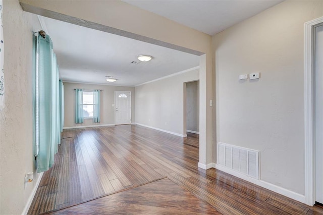 spare room featuring visible vents, ornamental molding, baseboards, and wood finished floors