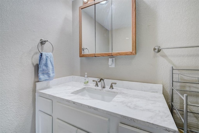 bathroom featuring vanity and a textured wall