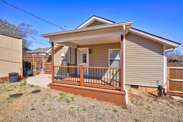 back of property with a porch, fence, and crawl space