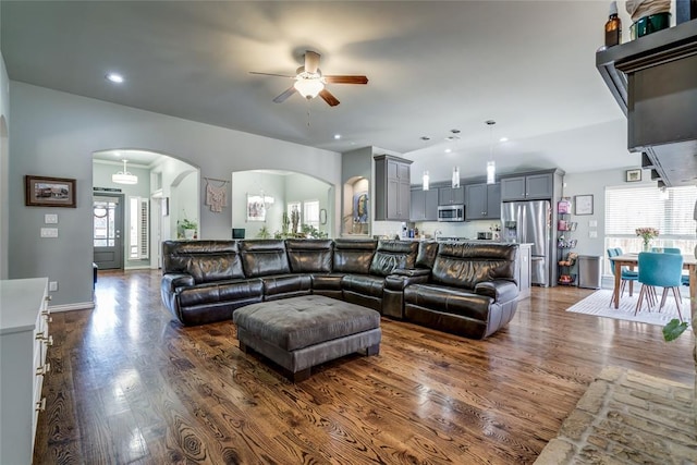 living area with arched walkways, a healthy amount of sunlight, and dark wood finished floors