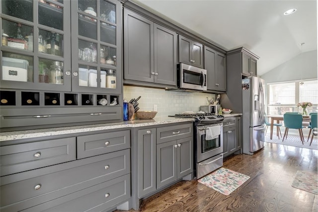 kitchen with tasteful backsplash, gray cabinetry, dark wood finished floors, lofted ceiling, and stainless steel appliances