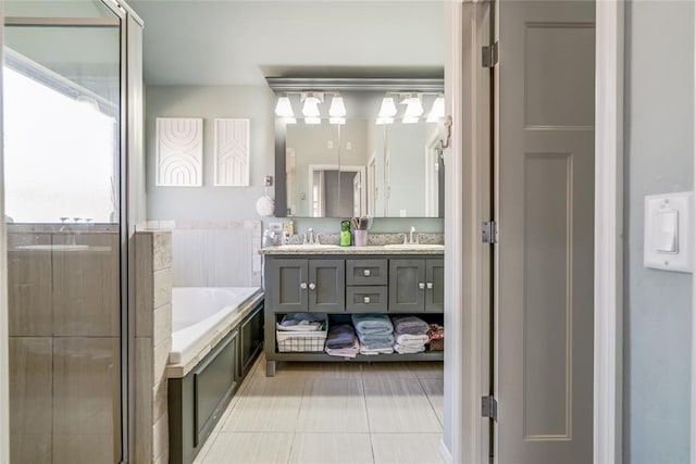 bathroom with a bath, tile patterned floors, double vanity, and a sink