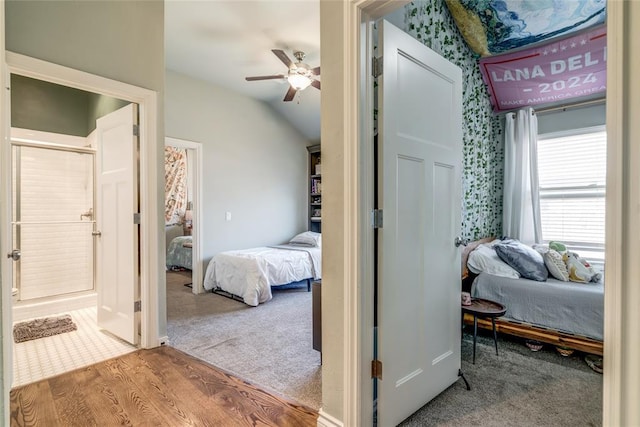 bedroom with wood finished floors, a ceiling fan, vaulted ceiling, carpet flooring, and connected bathroom