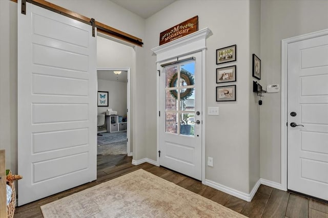 entryway featuring dark wood-style floors, baseboards, and a barn door