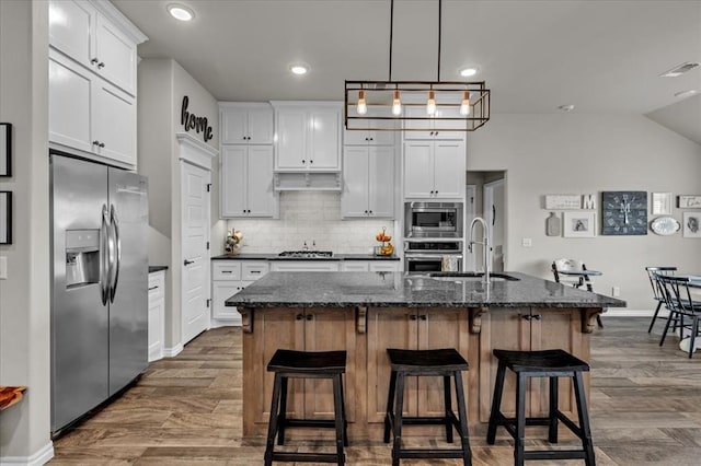 kitchen with dark wood-style floors, visible vents, a sink, under cabinet range hood, and appliances with stainless steel finishes