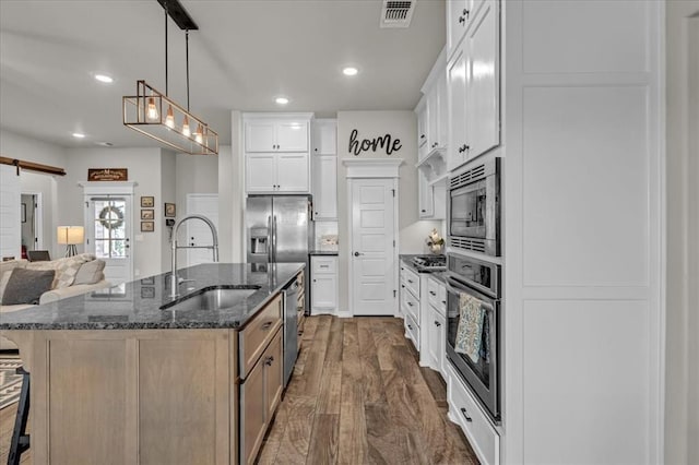 kitchen featuring visible vents, a breakfast bar area, a barn door, stainless steel appliances, and a sink