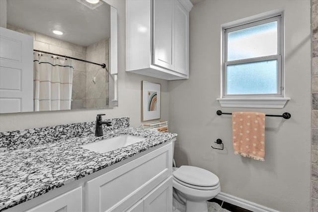 full bath featuring vanity, toilet, baseboards, and tiled shower