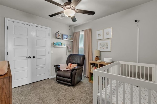 carpeted bedroom with visible vents, a nursery area, a closet, and a ceiling fan