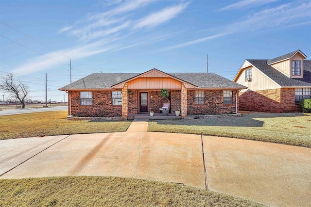 view of front facade with brick siding, a shingled roof, and a front yard