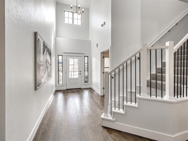 entrance foyer featuring baseboards, a chandelier, stairway, a towering ceiling, and wood finished floors