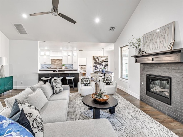 living room with visible vents, dark wood-style floors, a ceiling fan, and vaulted ceiling