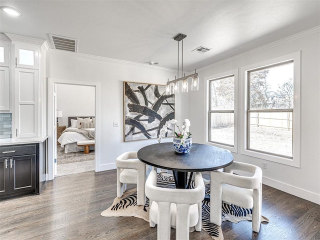 dining room with visible vents, crown molding, baseboards, and wood finished floors