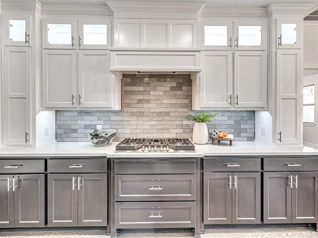 kitchen with light countertops, glass insert cabinets, gray cabinets, and stainless steel gas cooktop