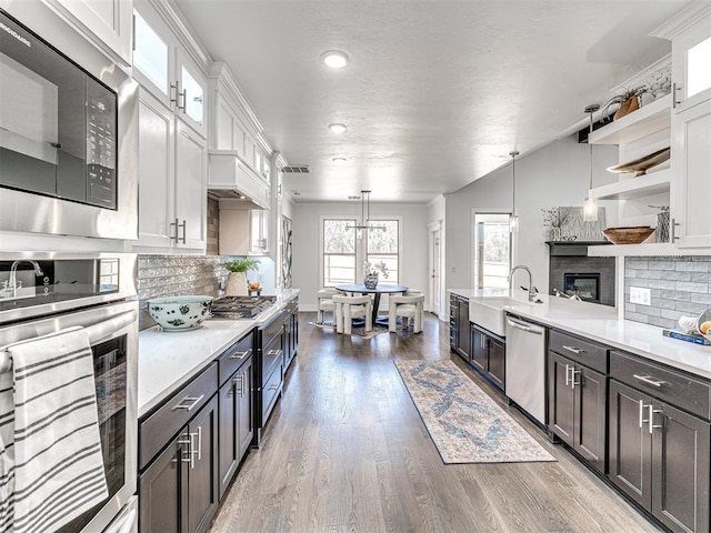 kitchen with appliances with stainless steel finishes, white cabinetry, light countertops, and a sink