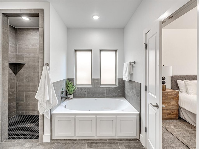 ensuite bathroom featuring connected bathroom, tiled shower, and a bath