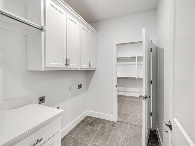 clothes washing area featuring cabinet space, electric dryer hookup, hookup for a washing machine, and baseboards