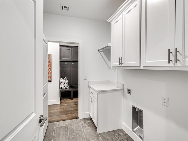 clothes washing area featuring wood finish floors, visible vents, cabinet space, baseboards, and hookup for an electric dryer