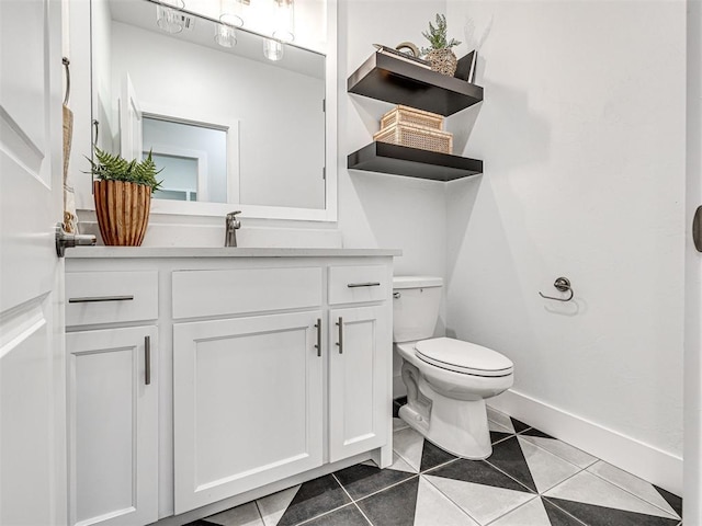 half bathroom featuring vanity, tile patterned floors, toilet, and baseboards