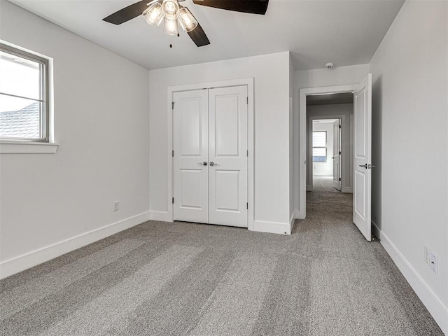 unfurnished bedroom with a closet, baseboards, carpet, and a ceiling fan