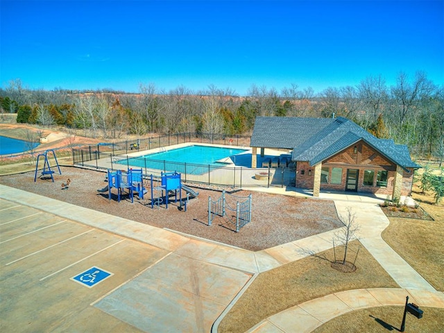 view of swimming pool with playground community and fence