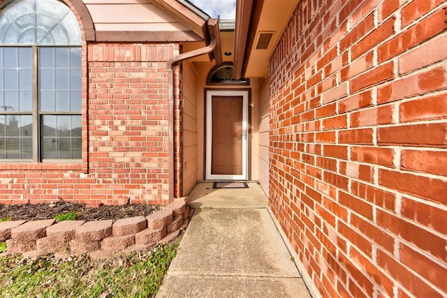 property entrance with visible vents and brick siding