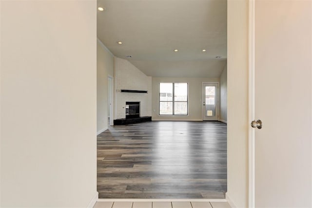 unfurnished living room featuring wood finished floors, recessed lighting, a fireplace, baseboards, and vaulted ceiling