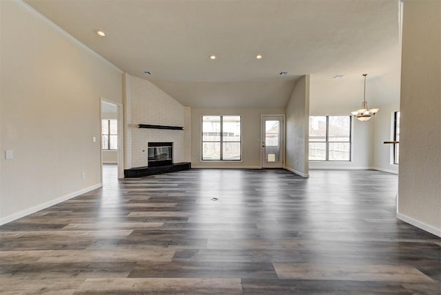 unfurnished living room featuring dark wood finished floors, an inviting chandelier, a brick fireplace, and vaulted ceiling