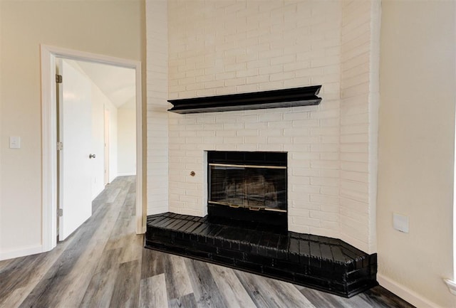 details with baseboards, a brick fireplace, and wood finished floors