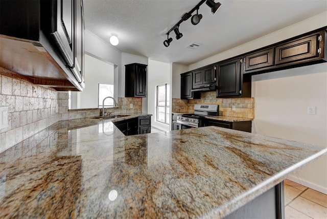 kitchen featuring light stone countertops, visible vents, a sink, stainless steel range, and backsplash