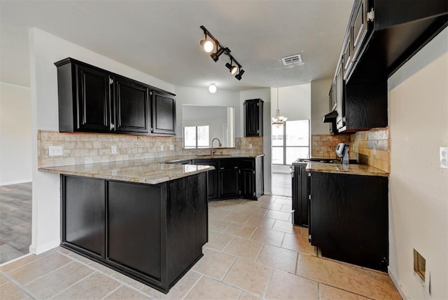 kitchen with visible vents, a sink, dark cabinetry, a peninsula, and stove