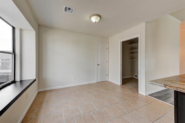 unfurnished room featuring visible vents, baseboards, and ornamental molding