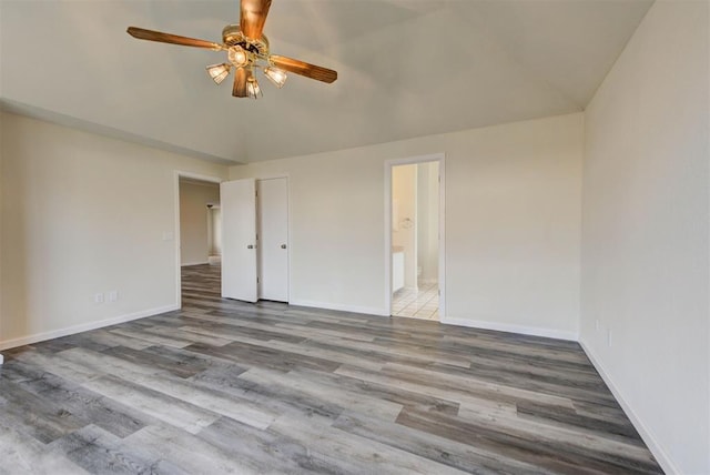 spare room featuring vaulted ceiling, a ceiling fan, baseboards, and wood finished floors