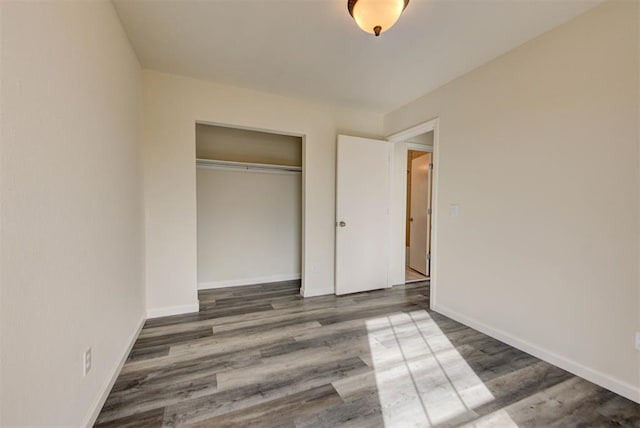 unfurnished bedroom with wood finished floors, a closet, and baseboards