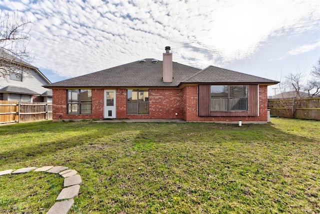 rear view of property featuring a lawn, brick siding, a fenced backyard, and a chimney