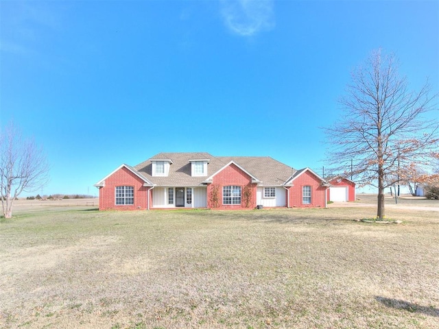 view of front of property featuring brick siding, a detached garage, and a front lawn