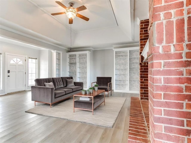 living room featuring wood finished floors, a tray ceiling, ceiling fan, and ornamental molding