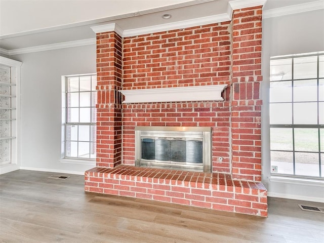 room details with visible vents, a brick fireplace, crown molding, and wood finished floors