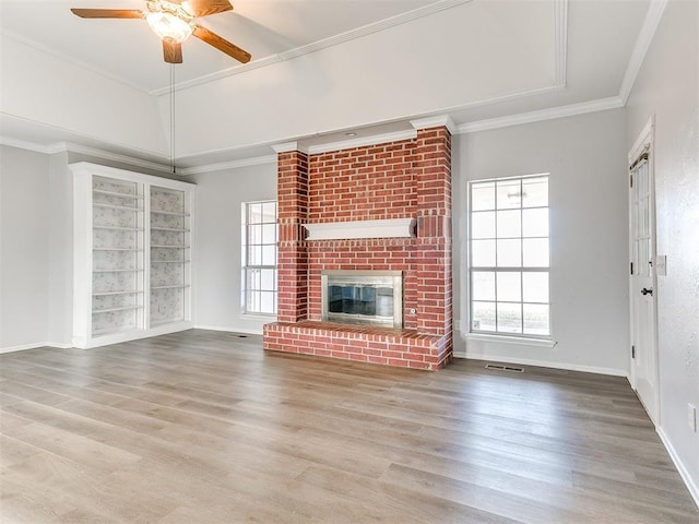 unfurnished living room with visible vents, wood finished floors, a fireplace, and crown molding