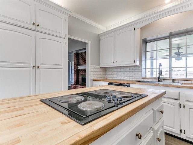 kitchen with a sink, black electric cooktop, wooden counters, and ornamental molding